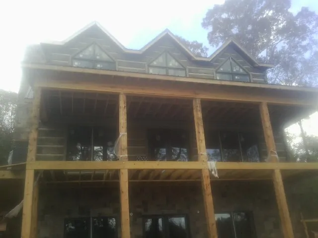 Dormers and porch framing on a large log home under construction — Roof Coating work by our crew in Darlington